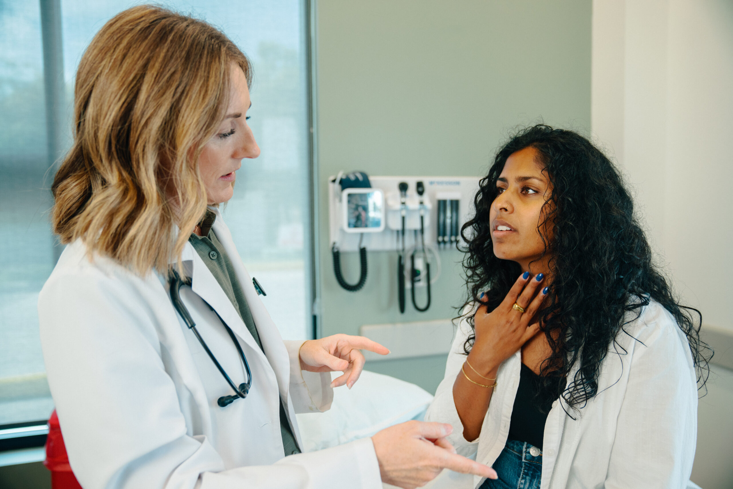 Female patient points to her throat discussing strep throat pain with an AFC provider